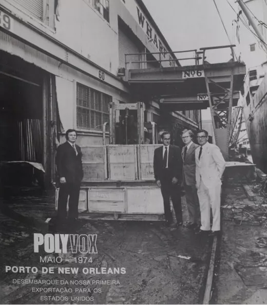 Imagem em preto e branco de 4 executivos da Polyvox no porto de News Orleans ao lado de várias caixas, para desembarcar a primeira exportação para os Estados Unidos, em maio de 1974.