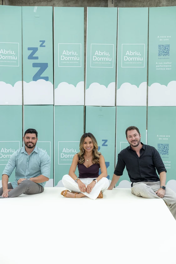 Equipe da Abriu Dormiu ao lado de um colchão embalado e expositor da marca