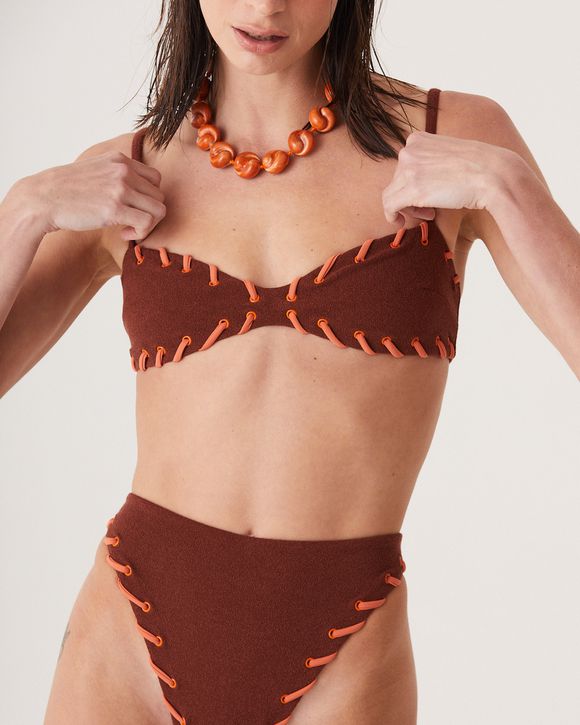 A modelo veste nosso Top Helena Café em lycra premium, alças finas e modelagem reta. Peça da collab August + NK Store com visual sofisticado e elegante.