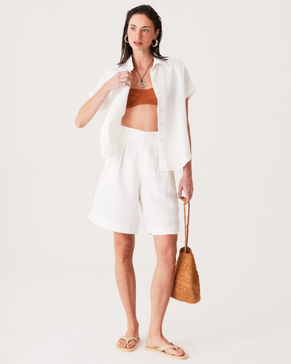 A modelo esta vestindo uma bermuda feminina em linho off white com corte elegante e caimento refinado.