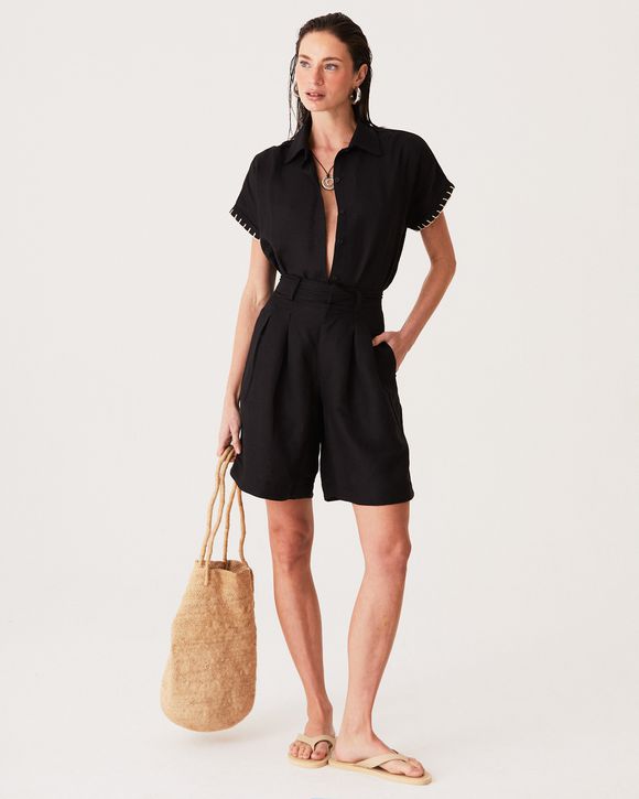 A modelo esta vestindo uma bermuda feminina em linho off white, com corte reto e caimento elegante, ideal para ocasiões casuais ou formais.