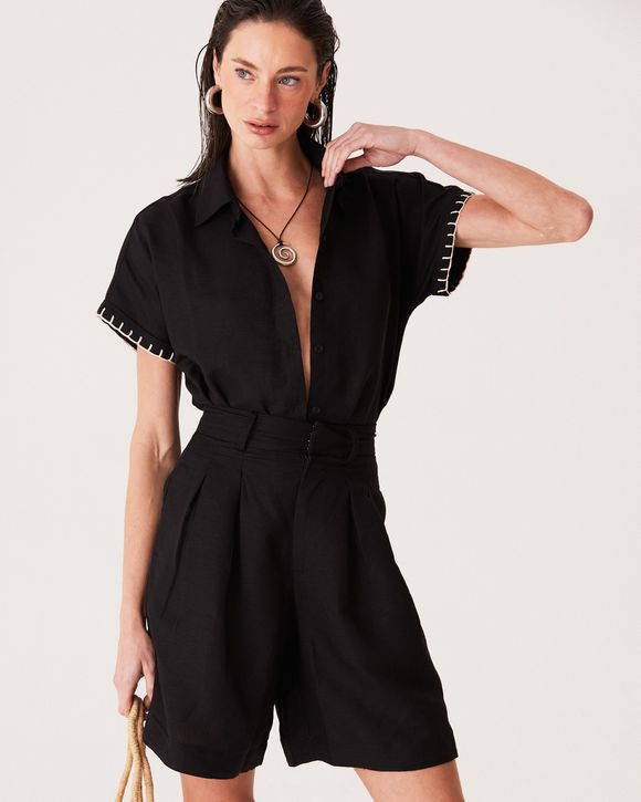 Modelo esta usando uma camisa preta de linho manga curta com botões e bordado delicado, estilo elegante e versátil.