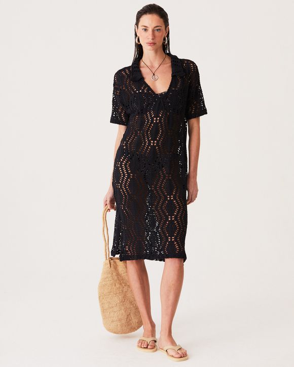 Modelo vestindo vestido longo de tricô preto com decote V e fendas laterais.