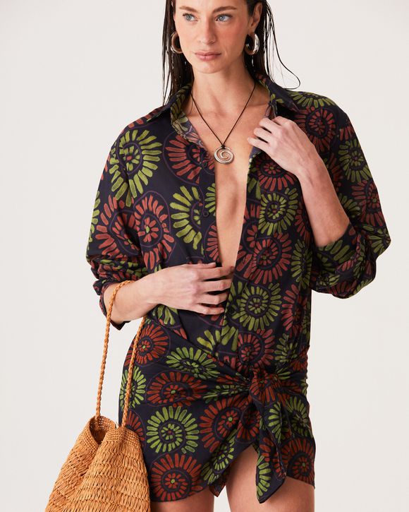 A Modelo esta vestindo uma Camisa unissex Gabi com estampa exclusiva de conchas e botões personalizados, confeccionada em algodão leve para o verão.