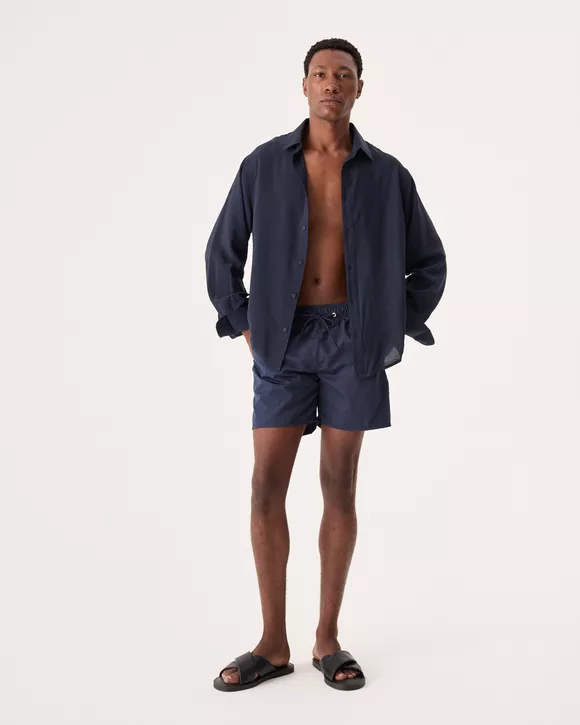 O Modelo esta vestindo uma Camisa masculina azul noite com botões personalizados e caimento confortável para o verão.