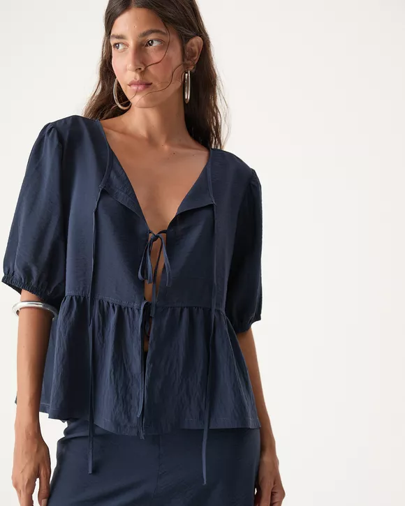 A Modelo esta vestindo uma Bata feminina azul noite em linho com amarrações ajustáveis e caimento sofisticado.