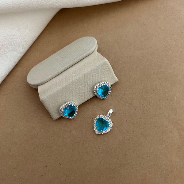 CONJUNTO BRINCO E PINGENTE CORAÇÃO ZIRCÔNIA AZUL CLARO BORDA CRAVEJADA