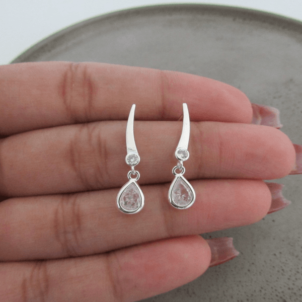 BRINCO TRAÇO BASE COM ZIRCÔNIA REDONDA NA PONTA E GOTA DE ZIRCÔNIA CRISTAL PENDURADA DE TARRAXA
